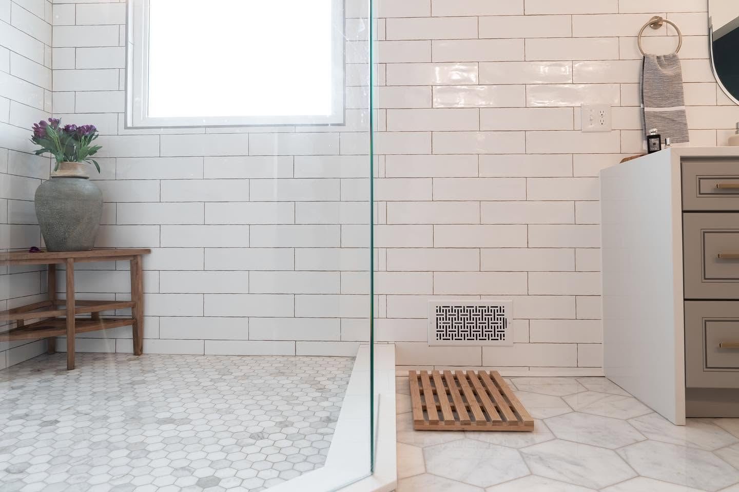 Glass shower with marble hexagon floor and a teak bench