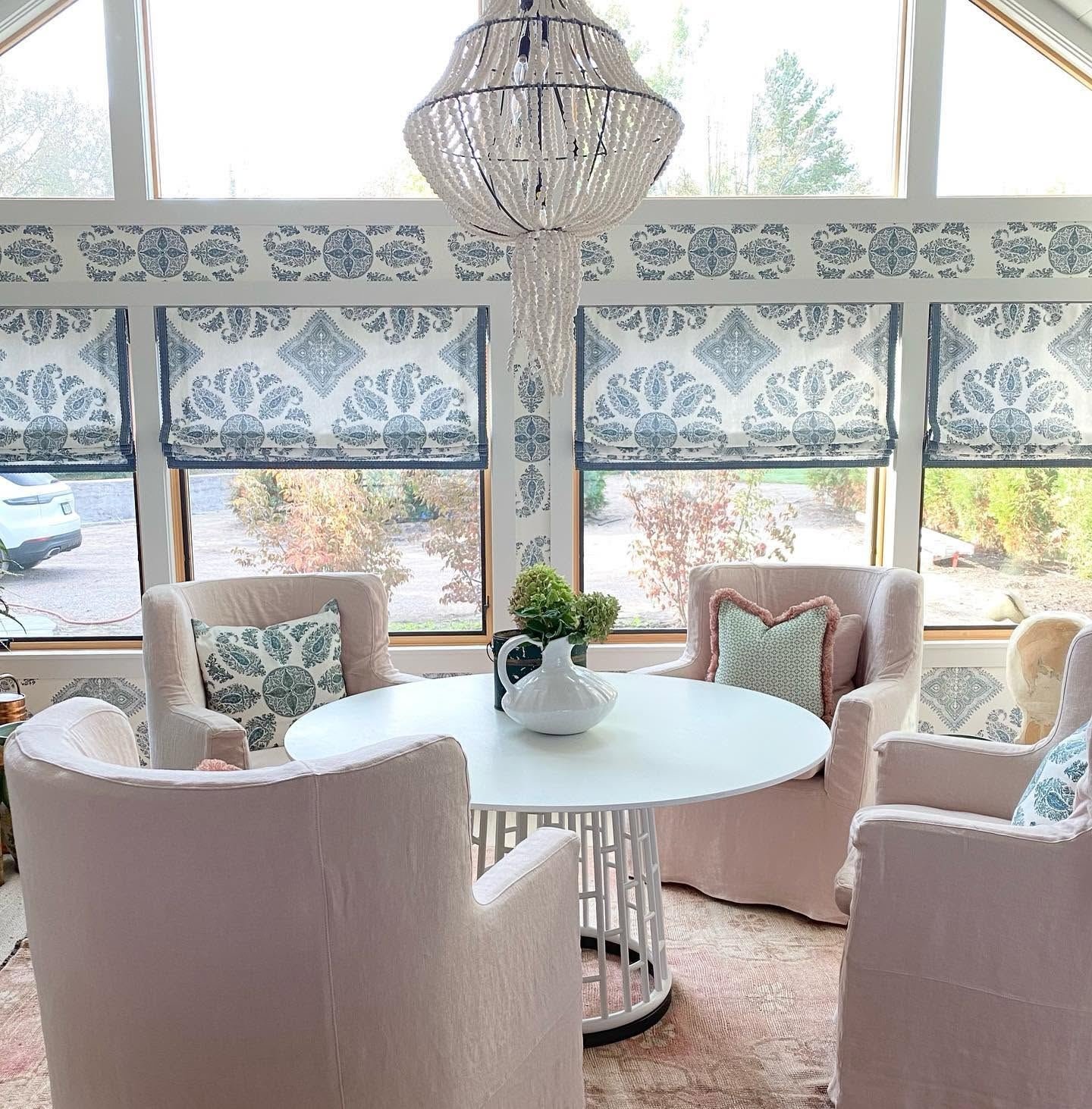 Sunroom with blue paisley Roman shades, beaded chandelier and blush linen chairs